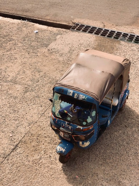 a small blue car parked on the side of a road