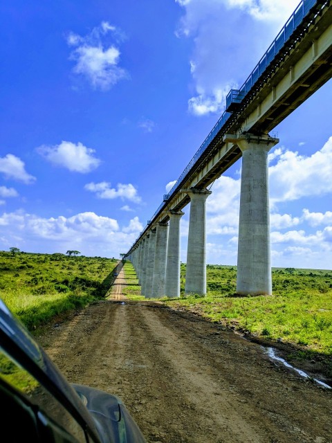 a car driving down a dirt road under a bridge