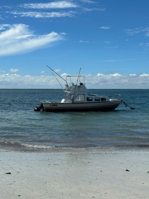 a boat is sitting in the water at the beach