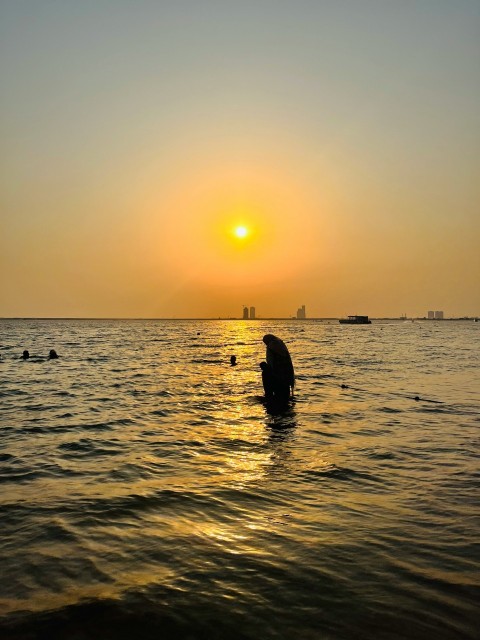 a person standing in the water at sunset