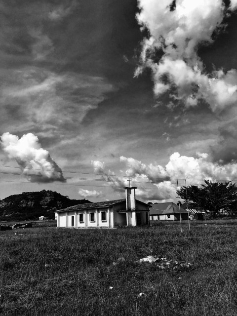 grayscale photo of a white house under cloudy sky