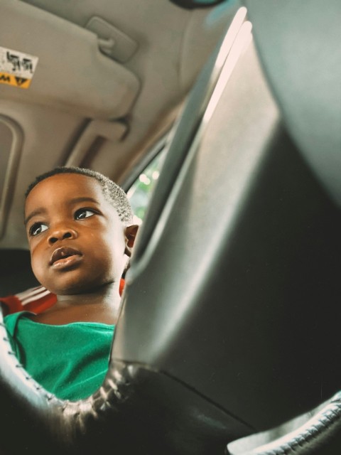 boy in green and white shirt sitting on car seat