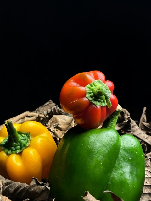 a group of three peppers sitting on top of leaves