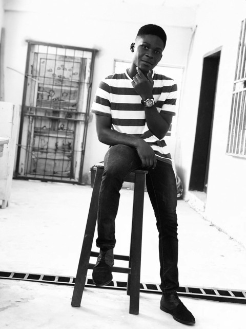 smiling man sitting on stool and touching his chin