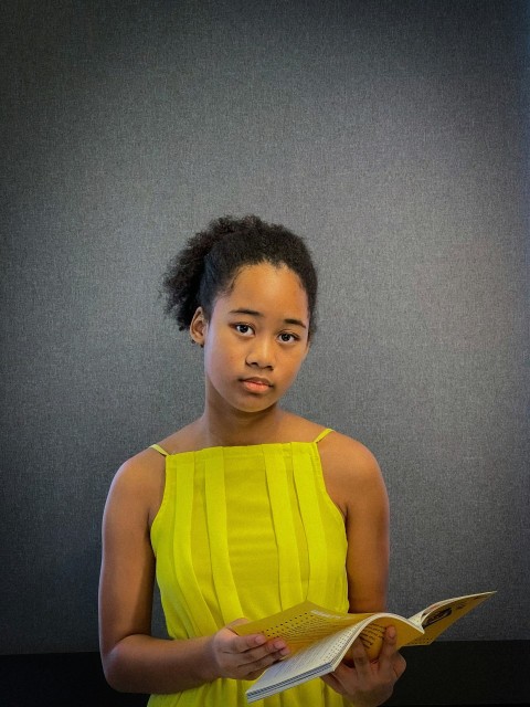 a woman in a yellow dress holding a book