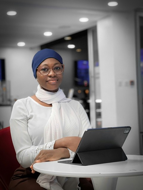 a woman sitting at a table with a laptop Xq