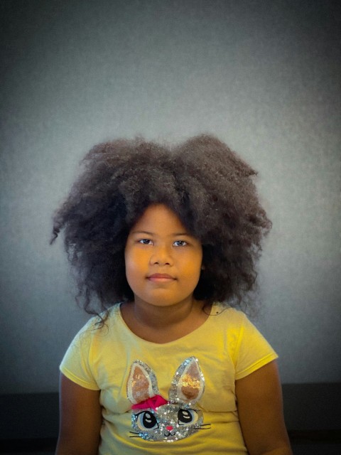 a little girl with a big afro sitting down