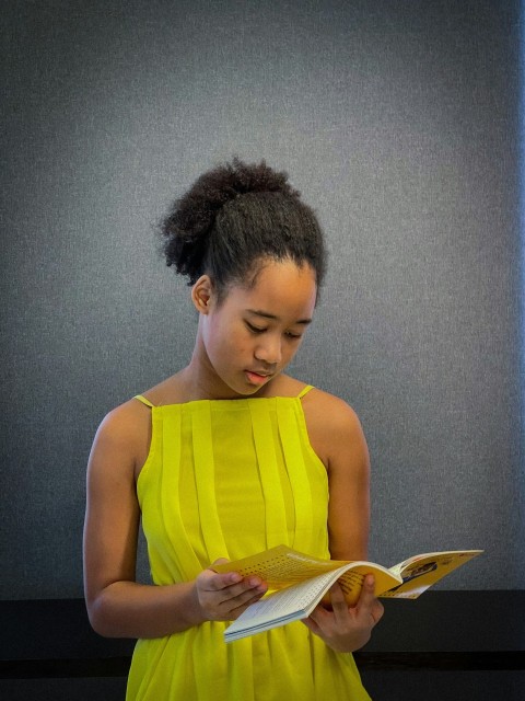 a woman in a yellow dress reading a book