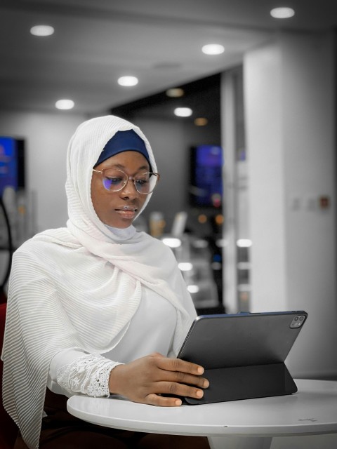 a woman in a headscarf is looking at a tablet