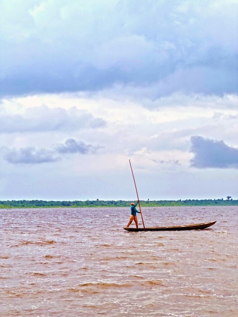 a man standing on a boat in the middle of a body of water