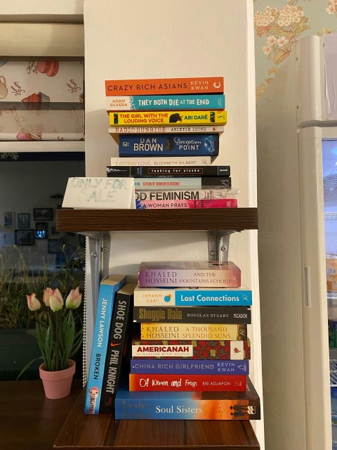 a stack of books sitting on top of a wooden shelf el_