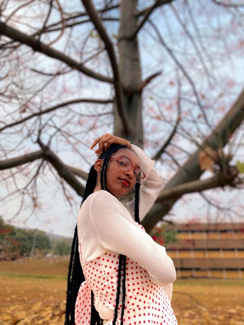 a woman standing in front of a tree with her hands on her head P