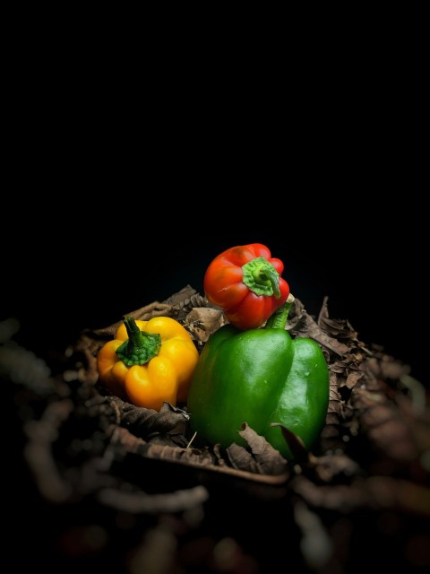 a group of peppers sitting on top of a pile of leaves