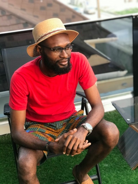 man in red crew neck t shirt and brown hat sitting on green grass during daytime