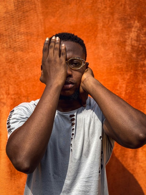 a man with glasses covering his eyes with his hands