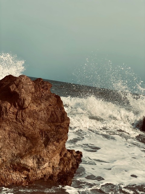 ocean waves crashing on brown rock formation during daytime S_HvS