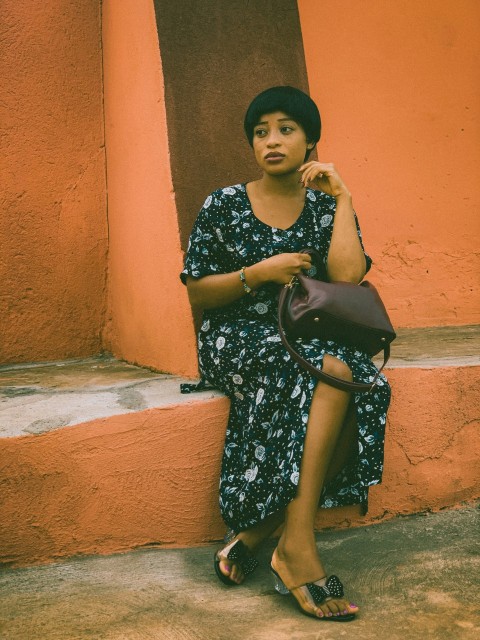 woman in blue and white floral dress sitting on brown concrete stairs