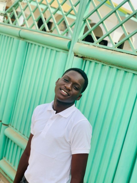 man in white polo shirt standing near blue metal wall during daytime