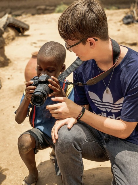 boy taking a knee and holding dslr camera beside man taking a knee