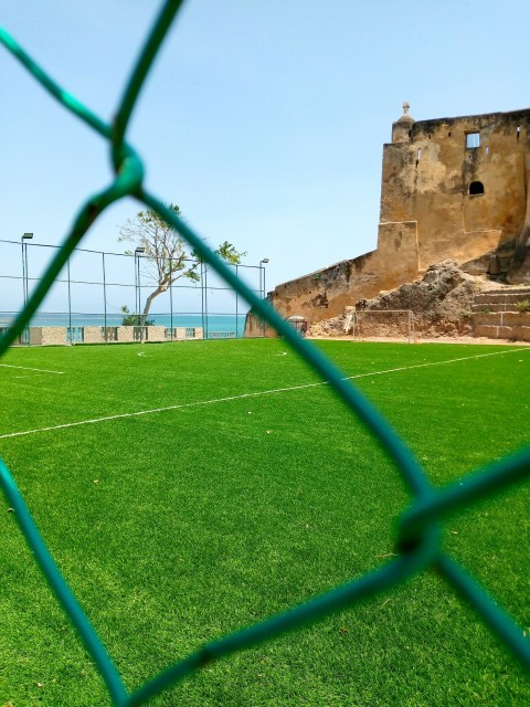 a soccer field behind a fence with a view of the ocean