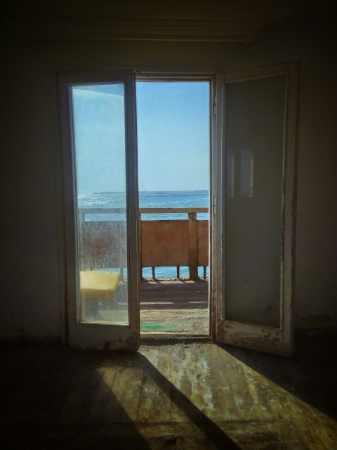 an open door leading to a balcony overlooking the ocean