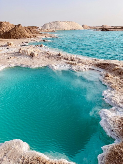 a body of water with rocks and a beach in the background