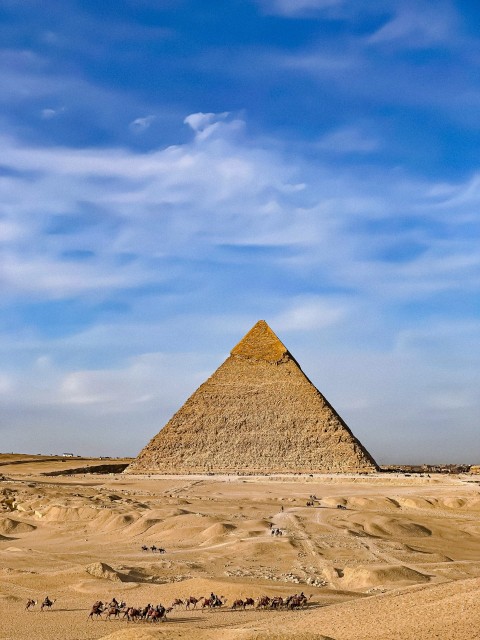 a group of people riding camels in front of a pyramid