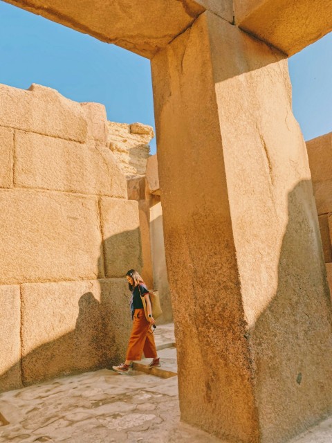 woman in brown coat standing near brown concrete wall during daytime Oiib4MSzF