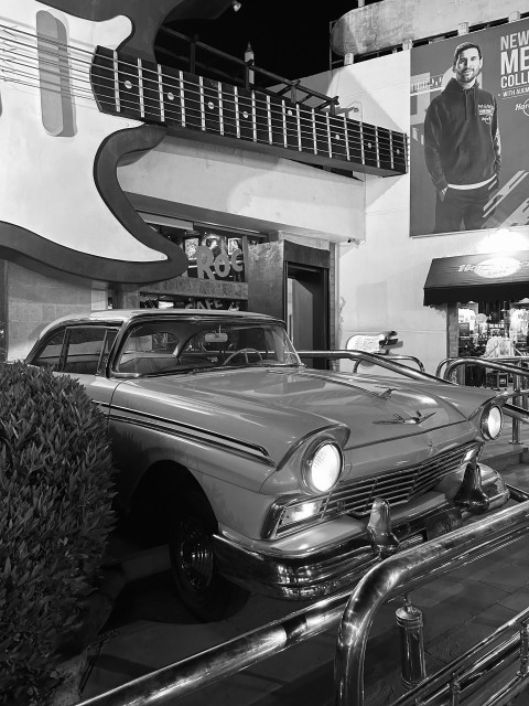 a black and white photo of a car parked in front of a building a3a