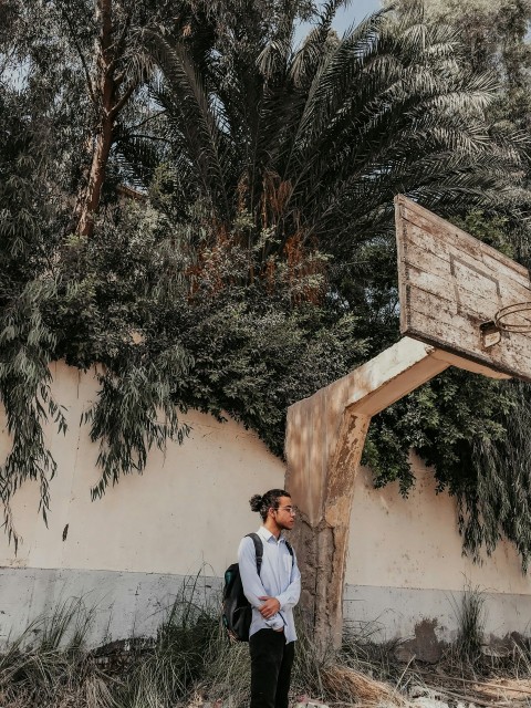 man in white shirt and blue denim jeans sitting on brown wooden bench