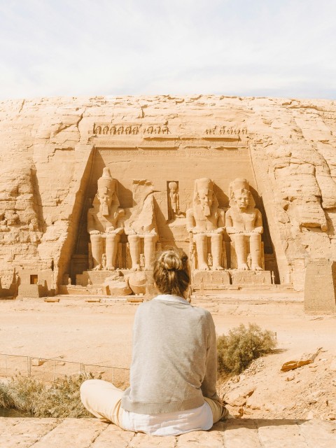 man in gray hoodie standing in front of brown rock formation during daytime