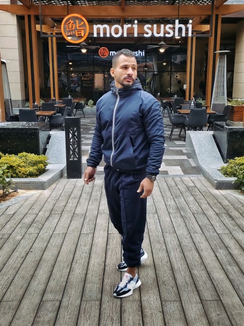 a man standing on a boardwalk in front of a restaurant