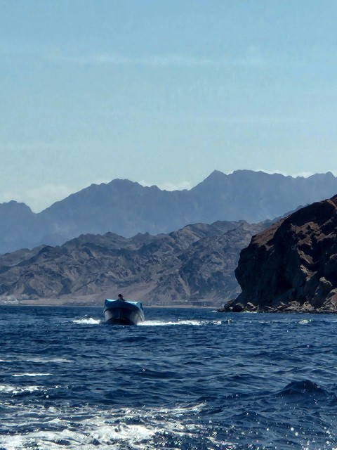 a boat in the middle of a body of water with mountains in the background 8pTTOVUN8