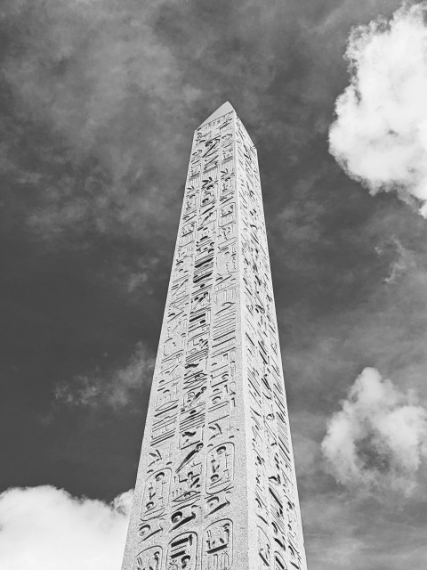 a tall obelisk with writing on it against a cloudy sky