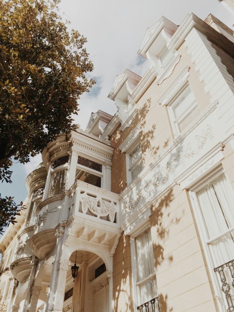 white painted concrete building near tree in low angle photography 0LO8JlWkc