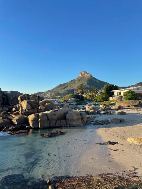 a rocky beach with a mountain in the background NgJv