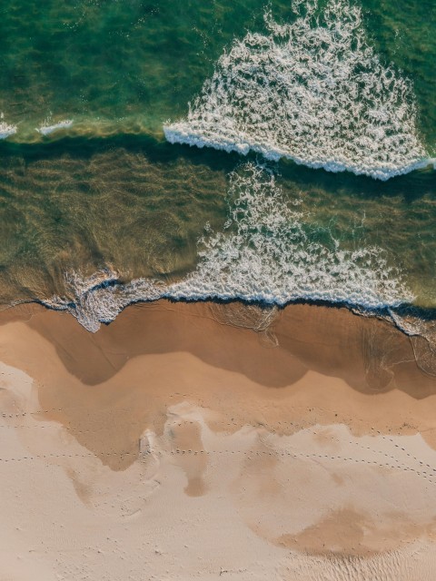 aerial view of sea waves crashing on shore during daytime