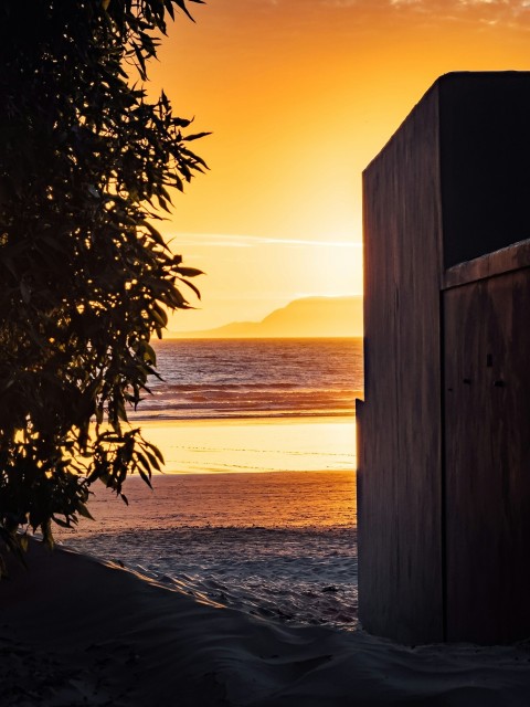 a wooden outhouse sitting on top of a sandy beach