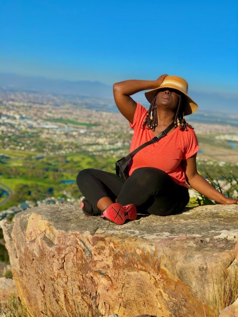 woman in black tank top and black pants sitting on brown rock during daytime