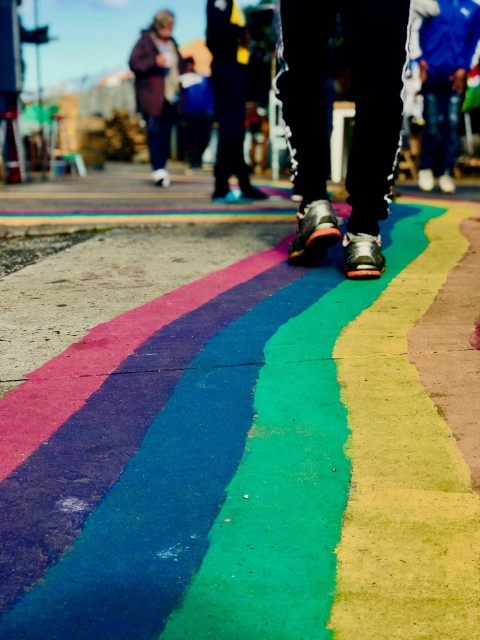 a person walking down a rainbow colored sidewalk KZ