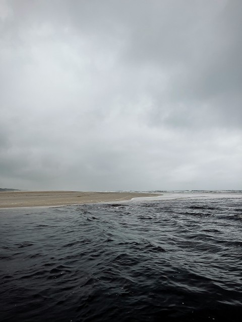 a large body of water under a cloudy sky rJtae