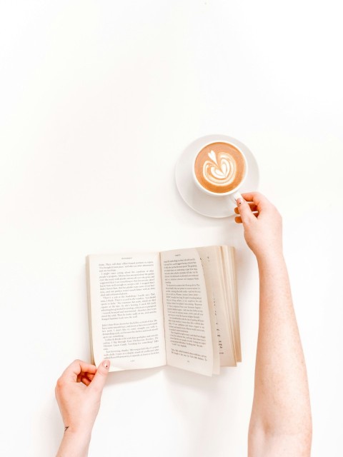 flat lay photography person holding mug with latte and book