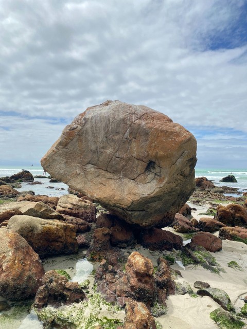 a large rock sitting on top of a sandy beach