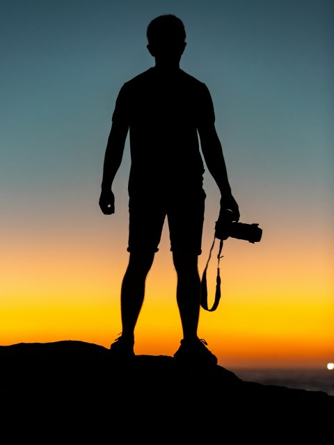 silhouette of man standing on cliff