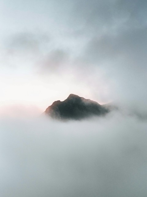 a mountain covered in fog and clouds on a cloudy day