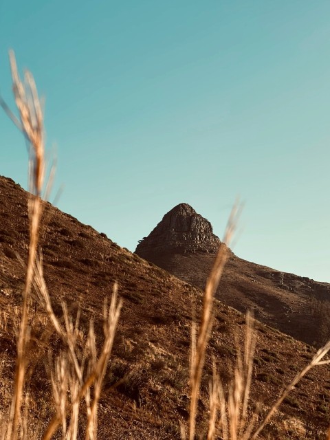 brown grass field near brown mountain under blue sky during daytime bqowz