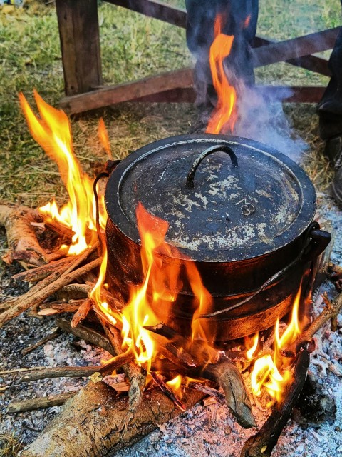 a pot on fire in a field next to a fence