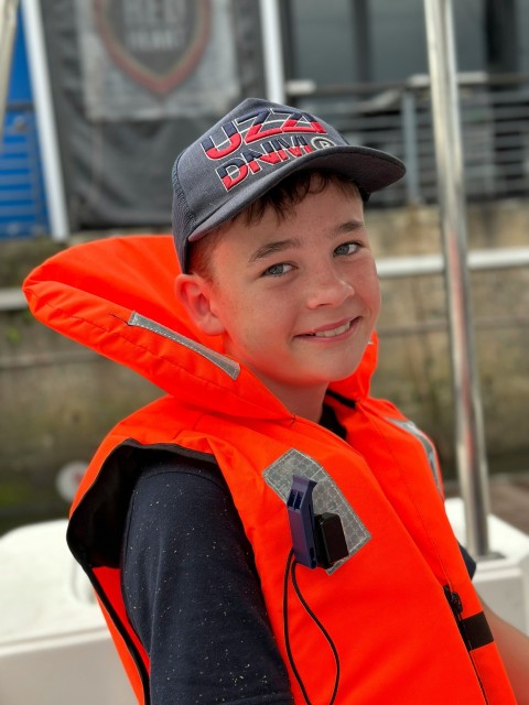 a young boy wearing an orange life jacket