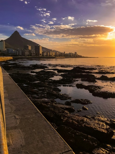 the sun is setting over the ocean with a city in the background