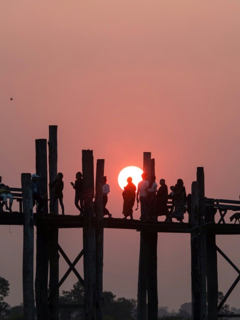 a group of people standing on top of a wooden bridge